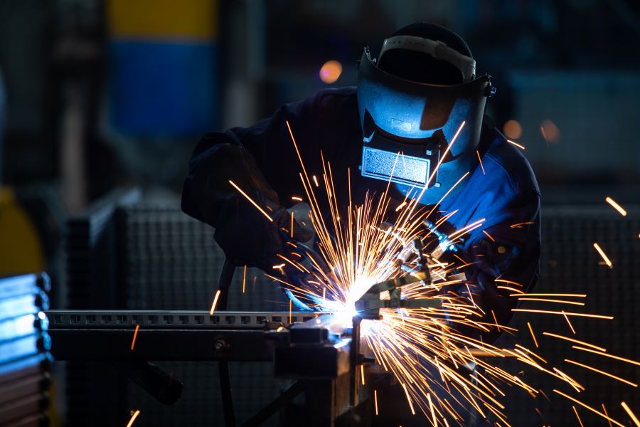 A man in welding gear welding a machine in Ontario