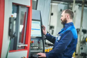 Industrial worker or service engineer operating cnc milling lather machine at factory in metal machining industry