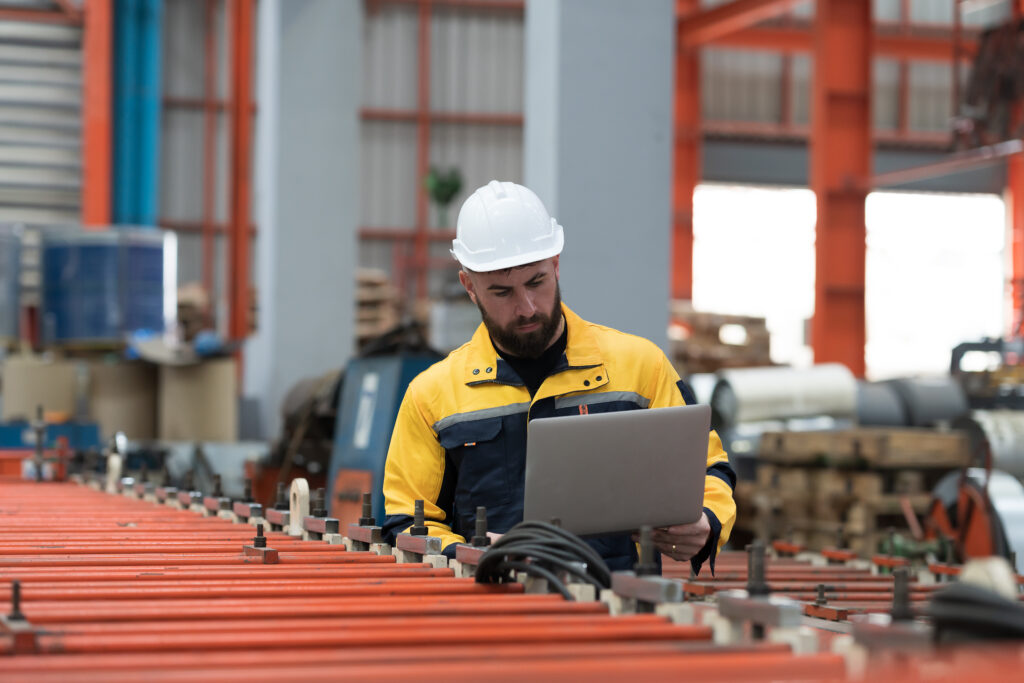 maintenance engineer in factory performing high-tech troubleshooting with a laptop